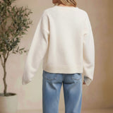 Back view of a woman wearing a cream-colored graced knit sweater with long sleeves and ribbed hem paired with blue jeans.