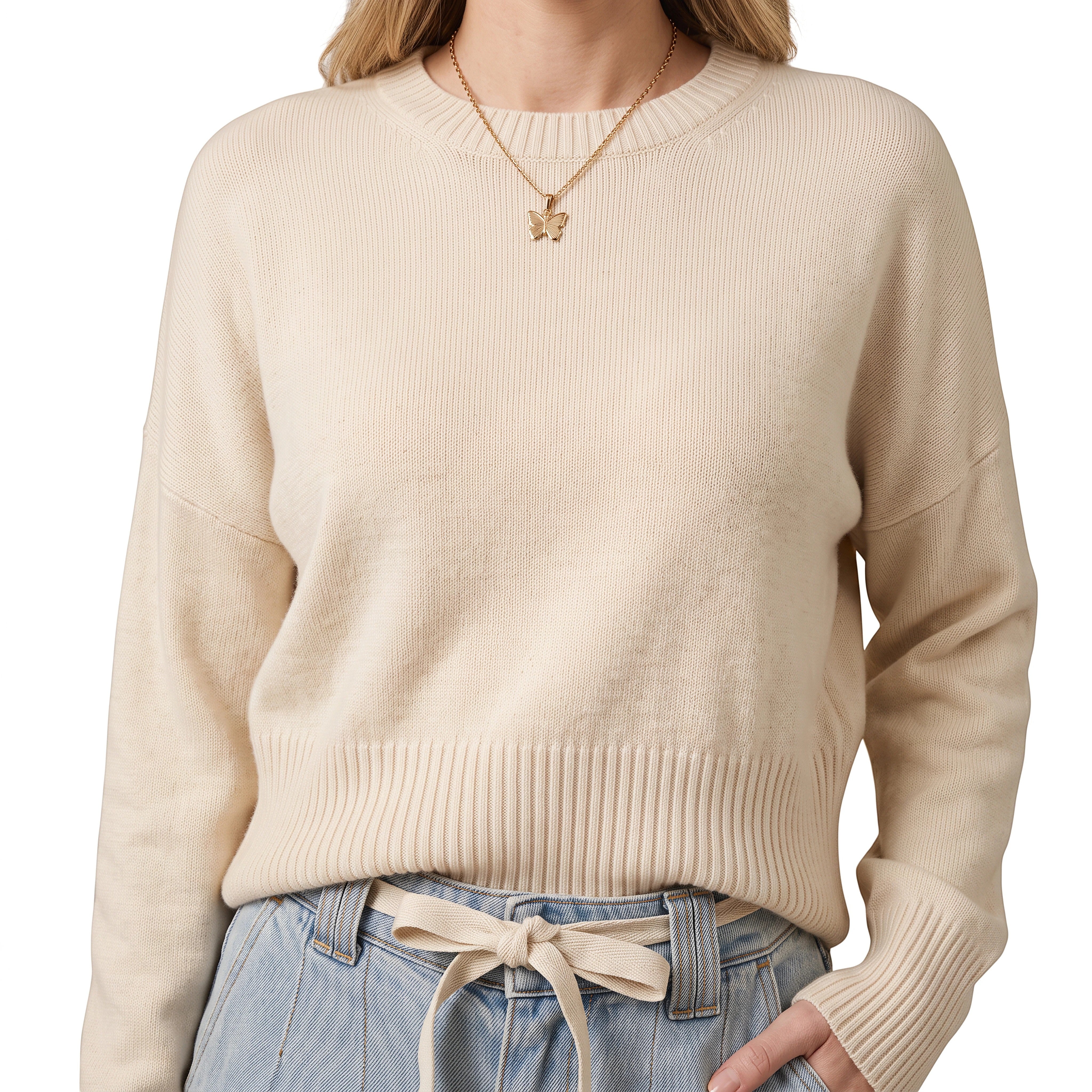 graced model wearing a cream ribbed knit sweater paired with light wash denim tie-front pants and a gold necklace
