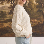 graced two tone textured weave sweater in cream worn by a woman with light blue jeans in a side profile view