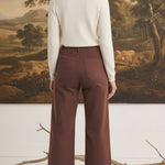 Back view of graced The Darcy wide-leg pants in cocoa brown with pocket detailing, worn with a cream sweater and boots.