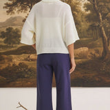 graced The Darcy navy wide-leg pants with back pocket detail worn with a white sweater and cream boots