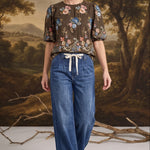 graced dark denim tie-front pants with a relaxed fit worn by a model in a floral blouse
