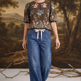 graced dark denim tie-front pants with a relaxed fit worn by a model in a floral blouse