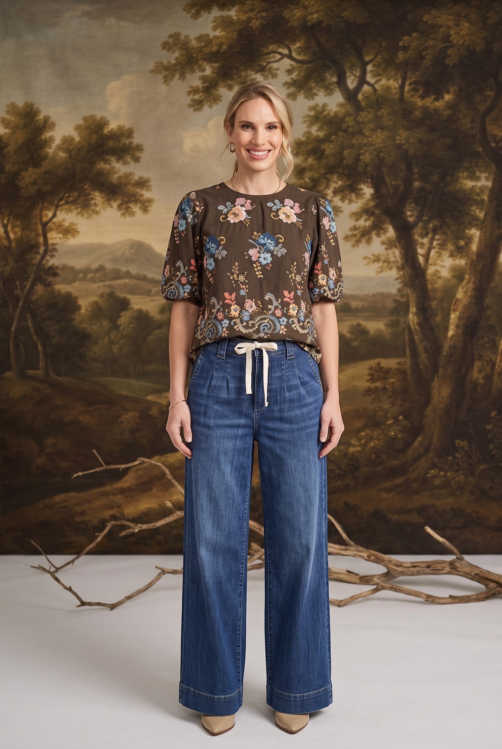 graced dark denim wide-leg pants with a tie-front waist worn by a model with a floral brown blouse