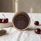 Graced Door County Cherry natural soy candle with a clear glass jar and label, designed for home fragrance and ambiance.