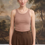 A model wearing a taupe graced Ellie Bra Free Tank with a ribbed texture, paired with brown trousers.
