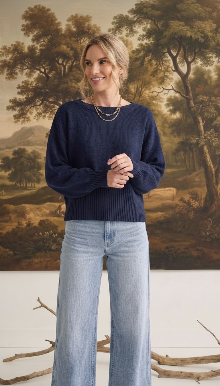 A woman wearing a navy graced Eloise crew neck sweater with dropped shoulders and wide ribbed cuffs and hem.