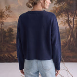 Back view of a woman wearing a navy graced Eloise crew neck sweater with dropped shoulders and wide ribbed hem.