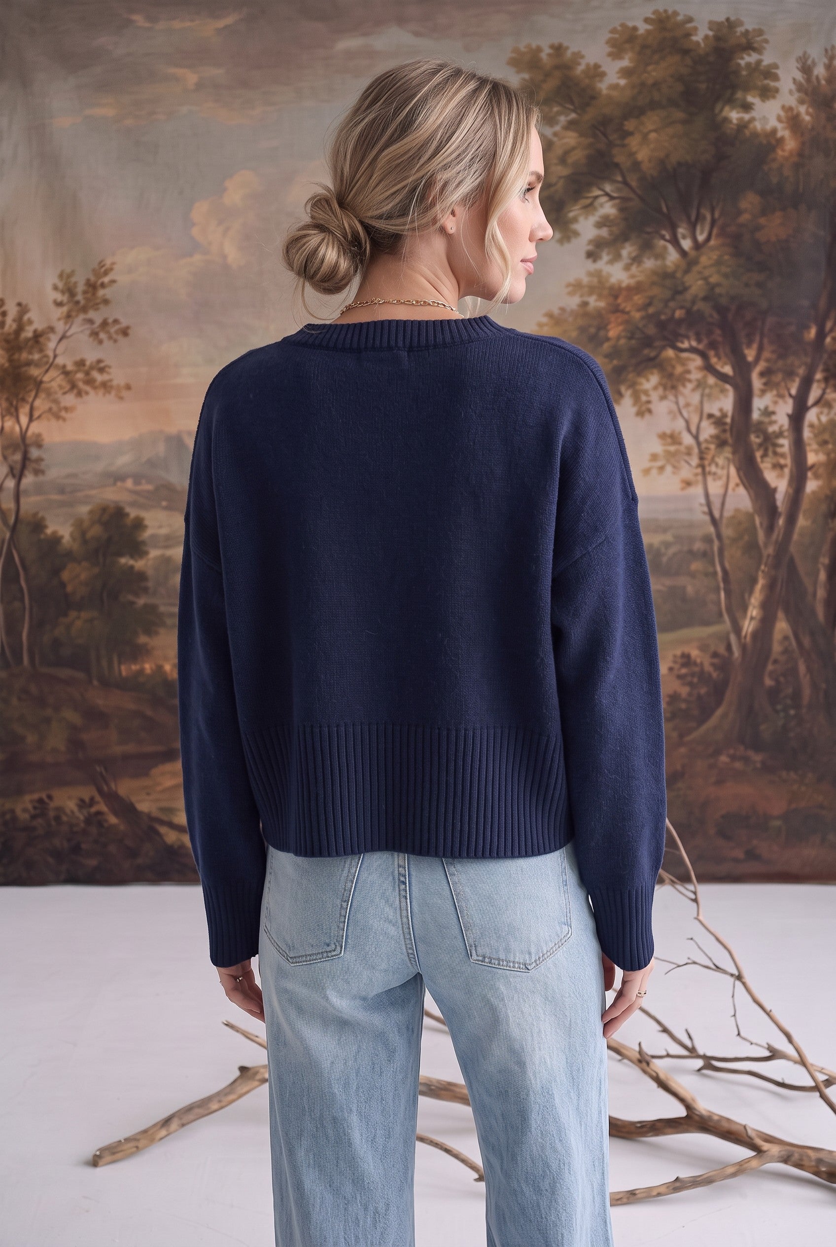 Back view of a woman wearing a navy graced Eloise crew neck sweater with dropped shoulders and wide ribbed hem.