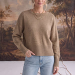 Model wearing a taupe graced Eloise crew neck sweater with dropped shoulders and wide ribbed hem, paired with denim.