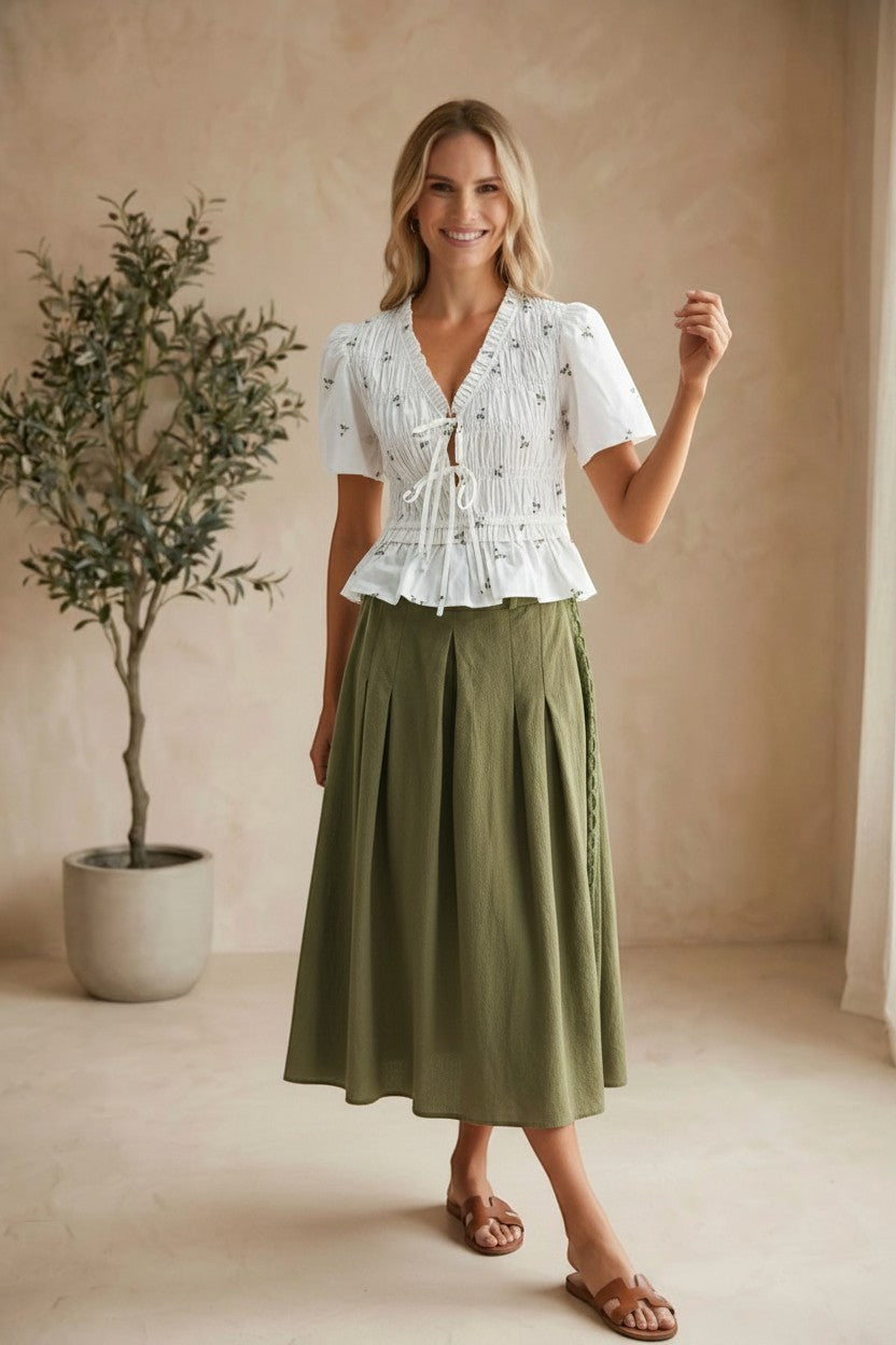 White embroidered peplum blouse by Camellia featuring pleated details, long sleeves, and intricate floral embroidery.