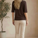 graced espresso brown short sleeve knit top worn by a blonde model with beige trousers in a studio setting