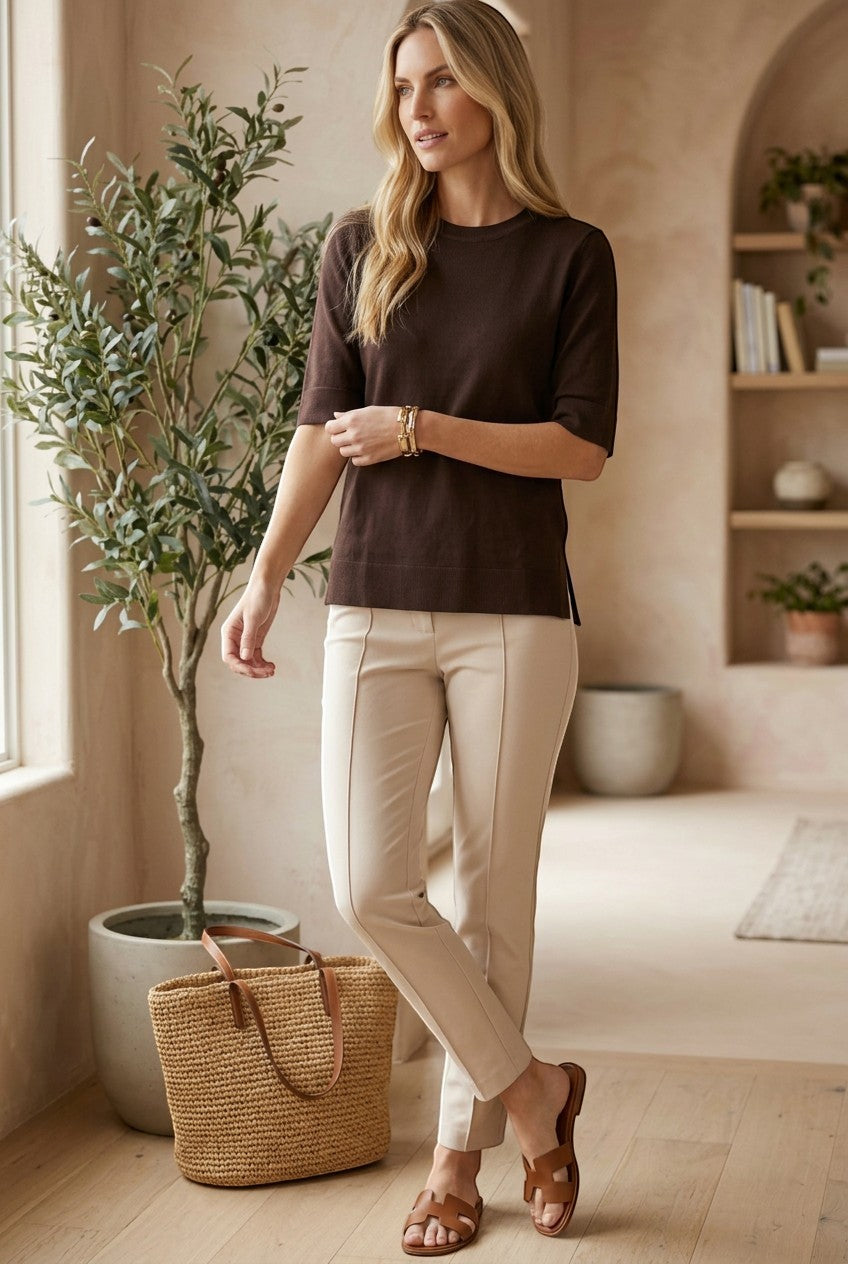 graced espresso brown short sleeve knit top worn by a woman with beige trousers and sandals in a bright room