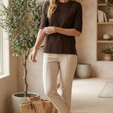 graced espresso brown short sleeve knit top worn by a woman with beige trousers and sandals in a bright room