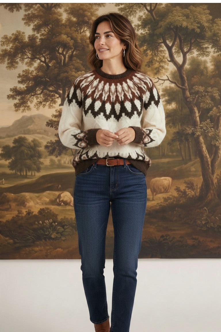 Model wearing a graced Fair Isle cable sweater in cream and brown with dark blue jeans and brown leather boots.