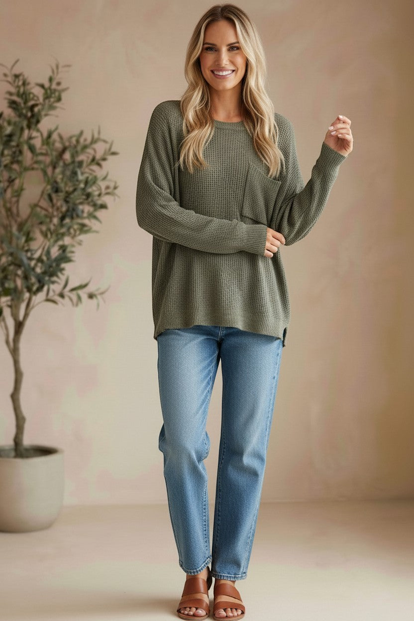 Model wearing a graced forest green dolman long sleeve knit sweater with a chest pocket and relaxed fit.