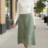 graced floral print midi skirt in green paired with a white ribbed top on a woman walking on a city sidewalk