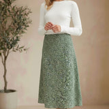 graced midi skirt in green floral print polyester worn by a blonde model with a white long-sleeve top