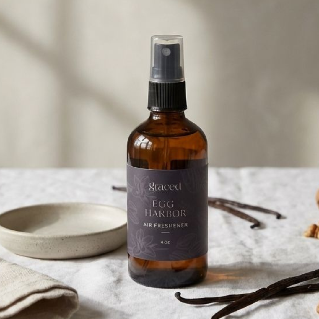 Bottle of 'Egg Harbor' air freshener on a textured surface with vanilla beans and a plate.
