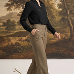 A model wearing graced houndstooth knit straight pants in brown paired with a black blouse in a studio setting