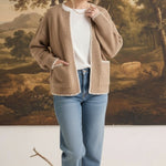 graced The Judy Open Cardigan in tan with white contrast stitching, worn by a model with jeans and a white top