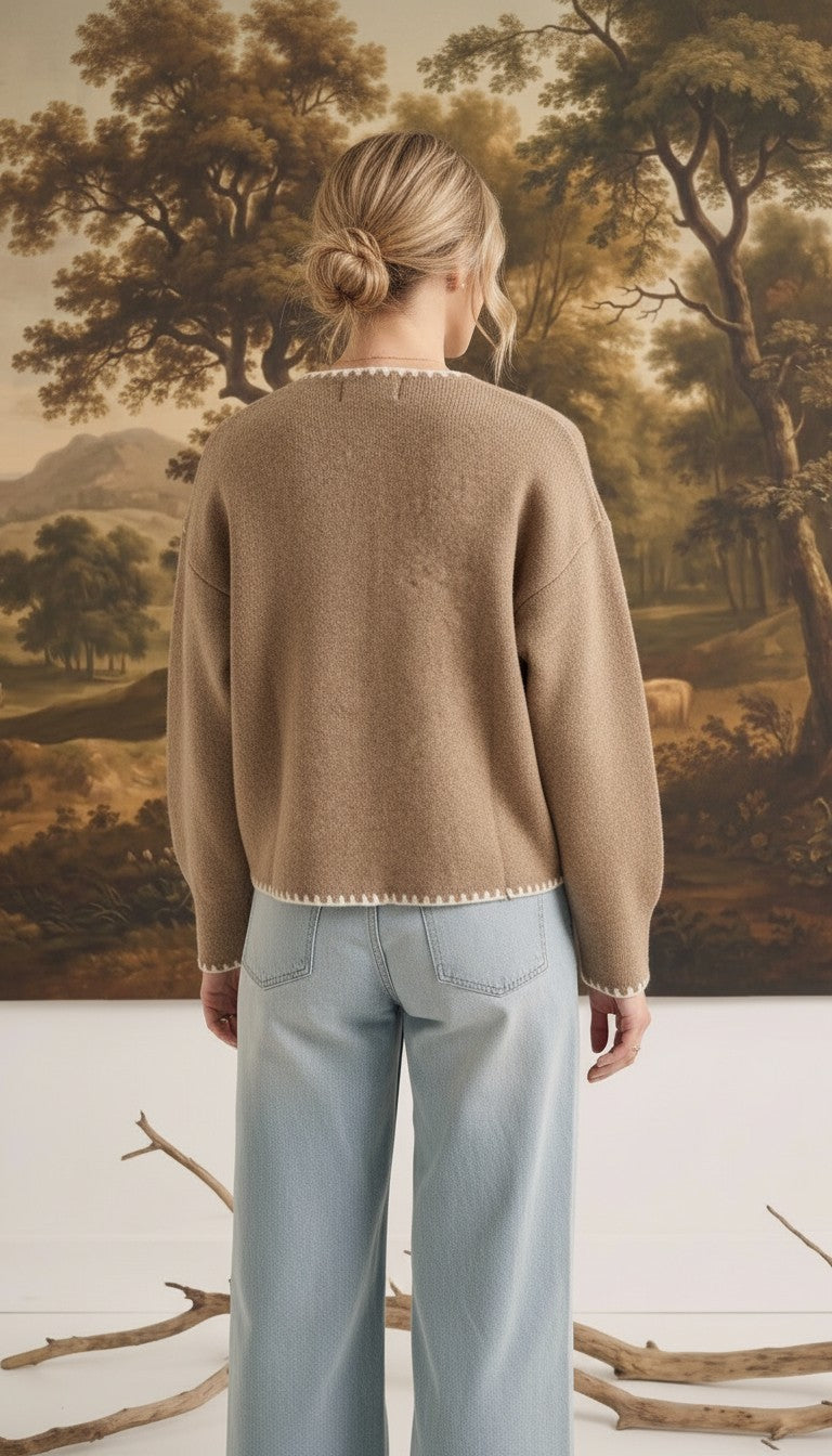 Back view of a woman wearing the graced Judy open cardigan in tan with white contrast stitching, paired with jeans.