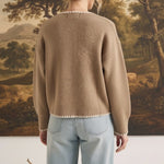 Back view of a woman wearing the graced Judy open cardigan in tan with white contrast stitching, paired with jeans.