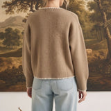 Back view of a woman wearing the graced Judy open cardigan in tan with white contrast stitching, paired with jeans.