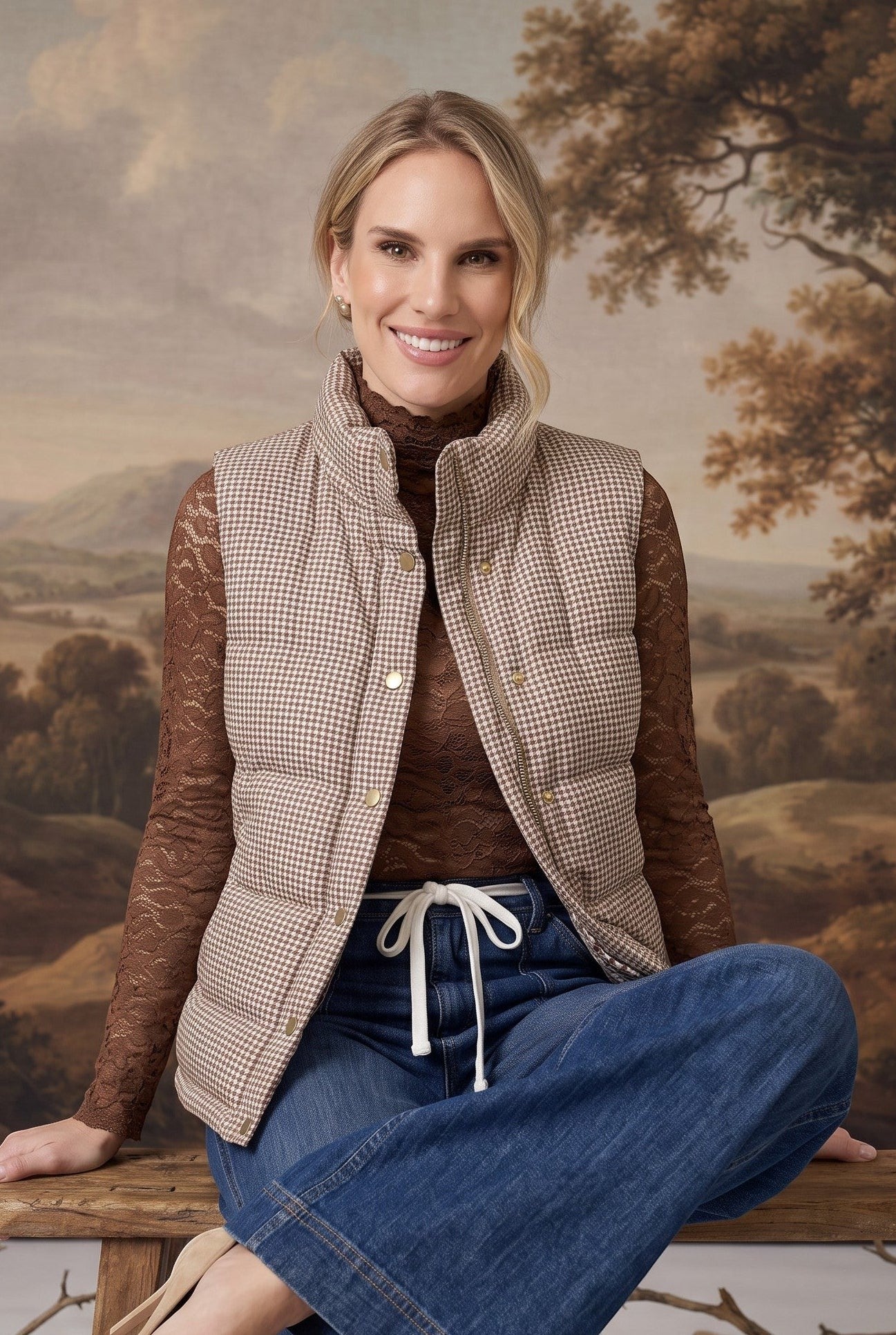 Model wearing a graced Karla gingham puffer vest in beige and white over a brown lace top and blue jeans.