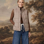 Model wearing a graced Karla gingham vest in tan over a brown lace top and wide-leg jeans against a landscape backdrop.