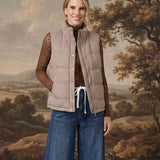 Model wearing a graced Karla gingham vest in tan over a brown lace top and wide-leg jeans against a landscape backdrop.