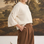 graced The Layla cream knit top with button-detailed sleeves worn by a blonde model with brown trousers