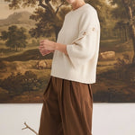 graced Layla cream button sleeve top with a relaxed fit worn by a model with brown trousers
