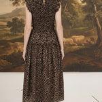 Back view of a woman wearing a graced leopard print sleeveless midi dress with a smocked waist and ruffled shoulders.