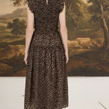 Back view of a woman wearing a graced leopard print sleeveless midi dress with a smocked waist and ruffled shoulders.