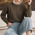 A model wearing graced soft denim barrel pants in light blue with a drawstring waist and a dark olive knit sweater.