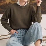A model wearing graced soft denim barrel pants in light blue with a drawstring waist and a dark olive knit sweater.