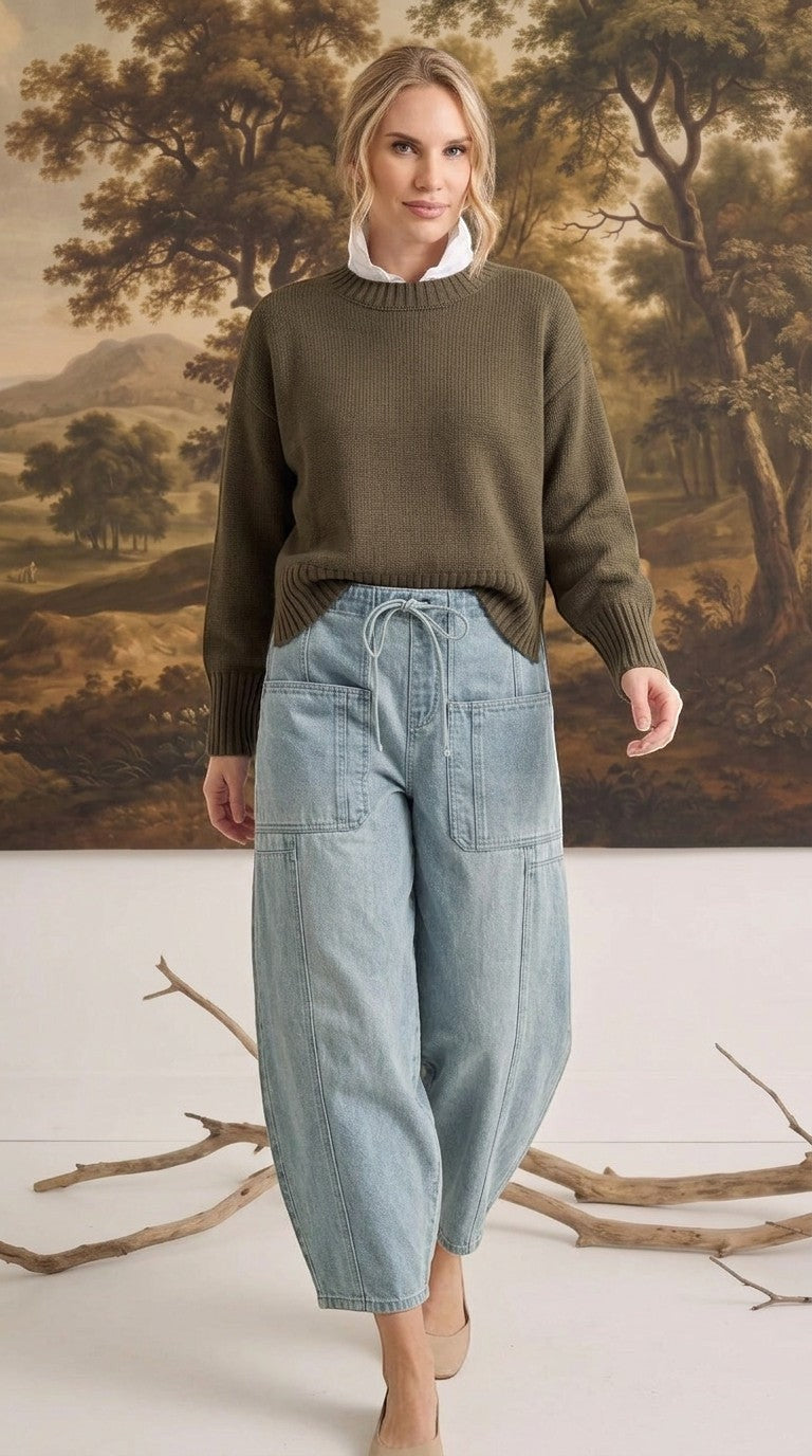 graced model wearing light wash denim barrel pants with large patch pockets and an olive green knit sweater