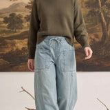 graced model wearing light wash denim barrel pants with large patch pockets and an olive green knit sweater