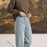graced soft denim barrel pants in light wash cotton with patch pockets worn by a woman with an olive green sweater