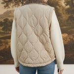 Back view of a woman wearing a graced Madilynne beige quilted vest with a plaid collar over a white sweater.