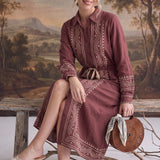 graced midi dress in maroon with contrast embroidery, button front, and drawstring waist worn by a seated woman