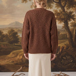 Back view of a model wearing a mocha chunky knit cardigan by graced, featuring a textured pattern and relaxed fit.