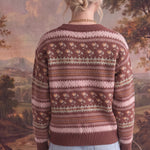 Back view of a woman wearing a graced mocha Fair Isle knit sweater with floral and geometric patterns and ribbed trim.