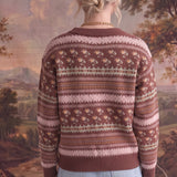 Back view of a woman wearing a graced mocha Fair Isle knit sweater with floral and geometric patterns and ribbed trim.