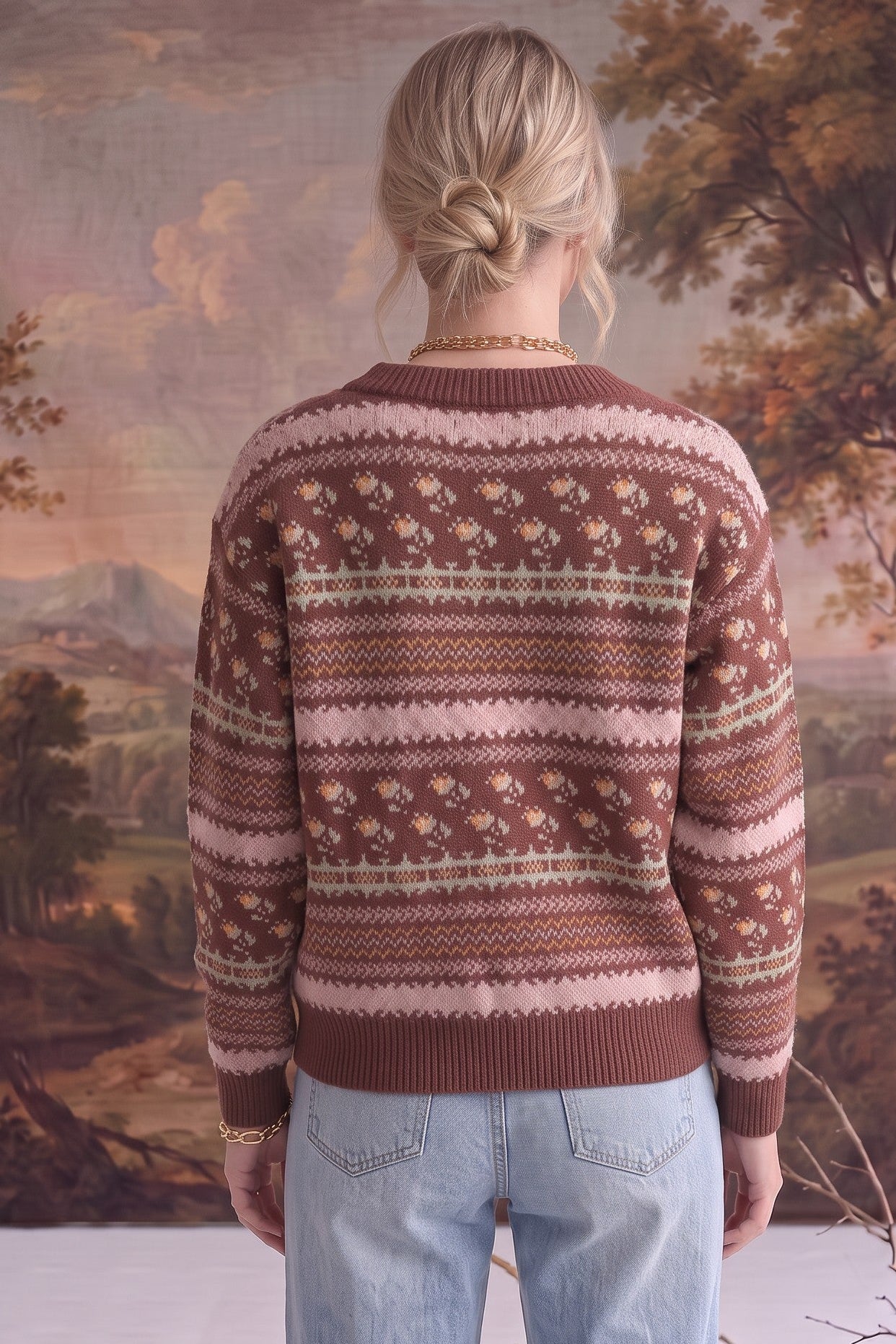 Back view of a woman wearing a graced mocha Fair Isle knit sweater with floral and geometric patterns and ribbed trim.