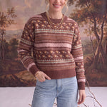 Model wearing a graced mocha Fair Isle knit sweater with floral and geometric patterns, styled with light wash jeans.