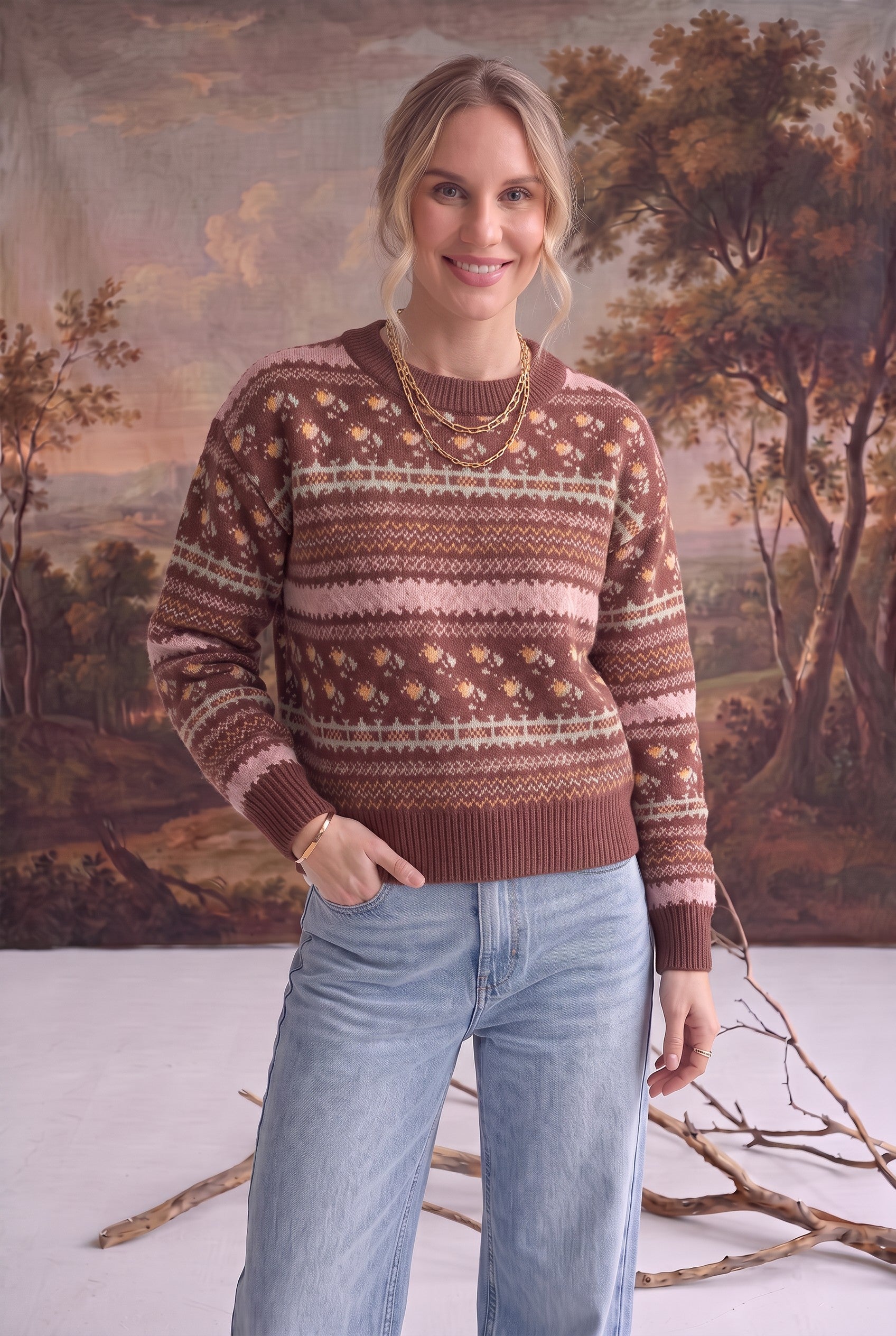 Model wearing a graced mocha Fair Isle knit sweater with floral and geometric patterns, styled with light wash jeans.