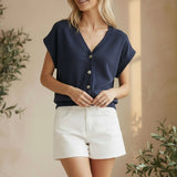 Navy sleeveless button-down top by in February, casual basic top with a collar and front buttons, shown on a plain background.