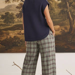 graced navy crew neck sweater vest with side buttons worn by a model with plaid trousers in a studio setting